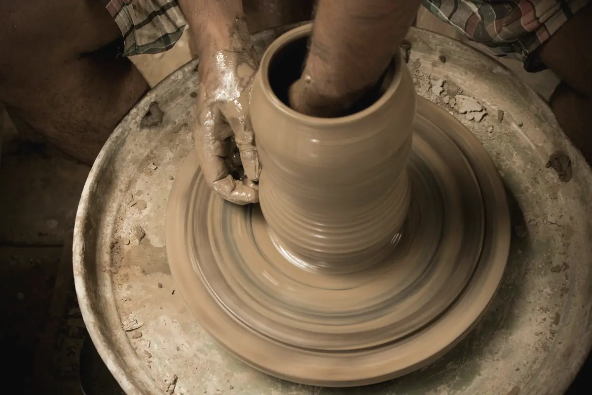 Manos dando forma a una pieza de barro en el torno